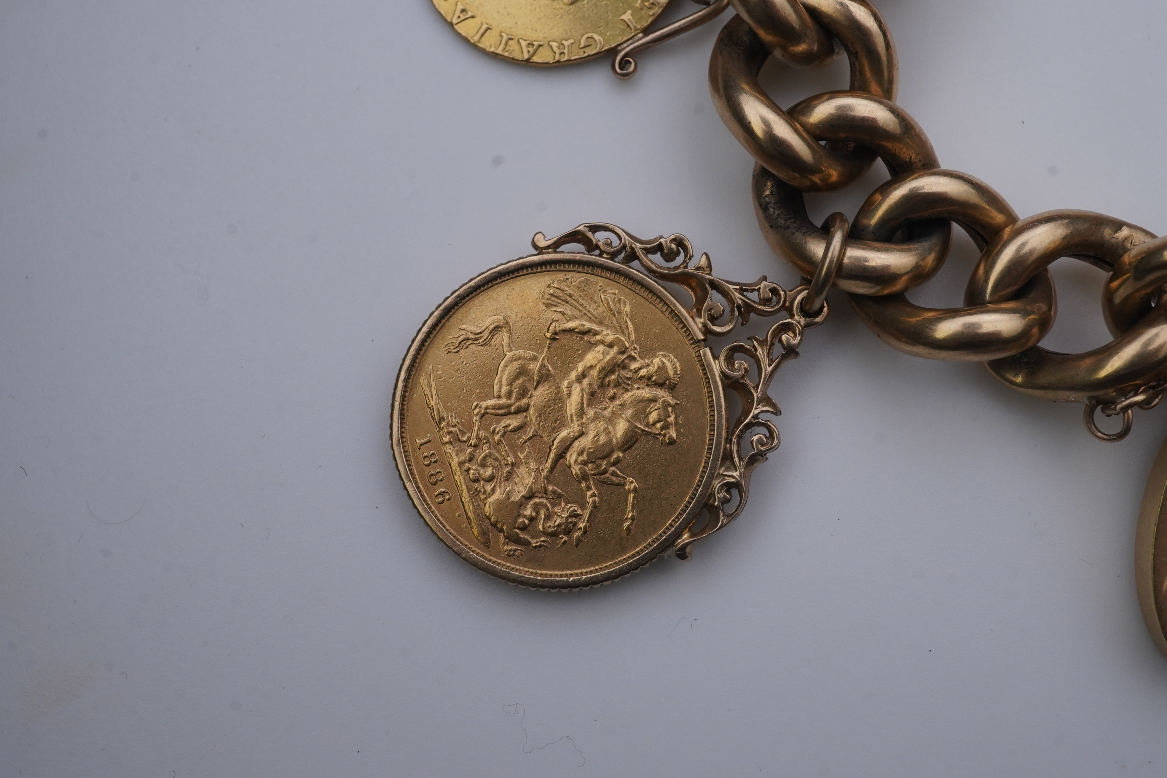 An Edwardian 18ct gold charm bracelet and five gold coin pendants